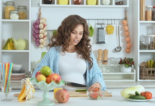 Beautiful pregnant woman with  food at kitchen