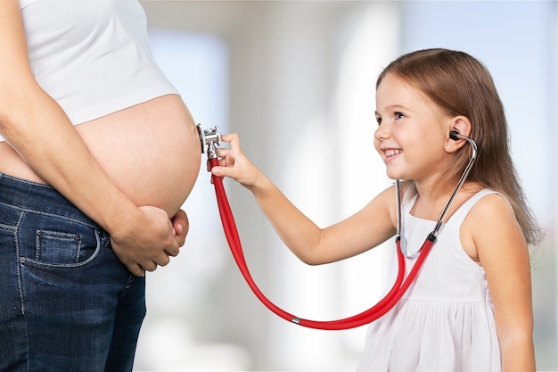 Beautiful pregnant woman with her daughter. Isolated on  background