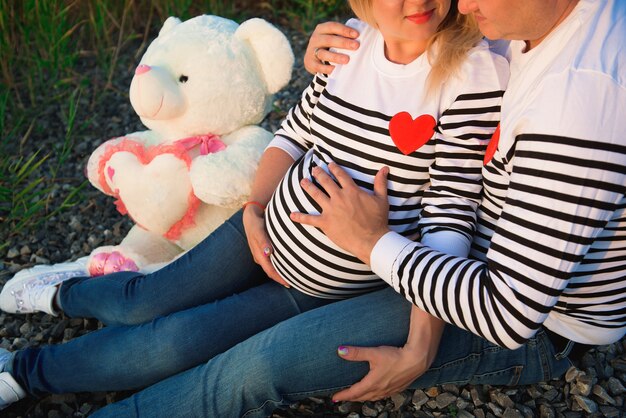 Bella donna incinta con la sua famiglia seduta in riva al fiume