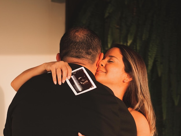 Beautiful pregnant woman with her husband with an echo in her baby's hand