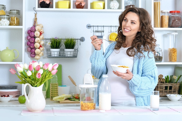 Beautiful pregnant woman with  milk at kitchen