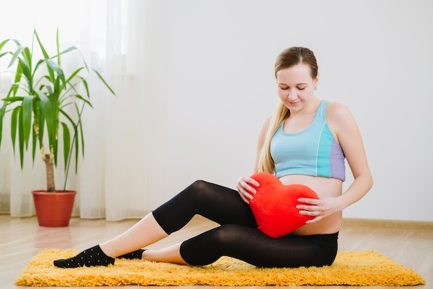 Beautiful pregnant woman with pillow in heart shape