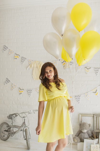 Beautiful pregnant woman in a yellow dress in the studio