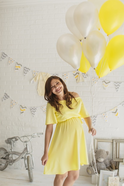스튜디오에서 노란 드레스를 입고 아름 다운 임신한 여자.