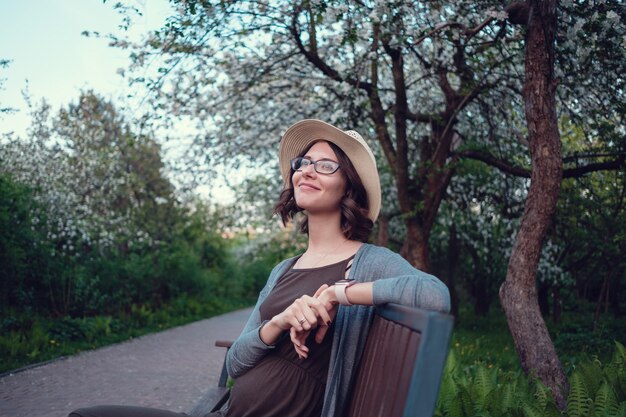 A beautiful pregnant young woman enjoys an evening walk through a beautiful green park.