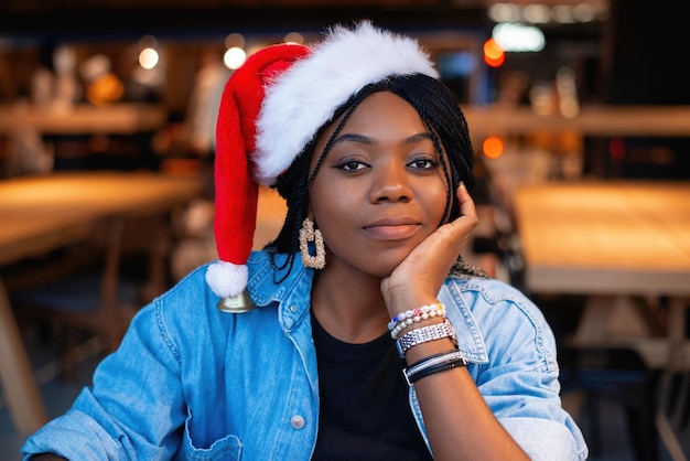 A beautiful pretty brunette with afro pigtails and dark skin in
a santa claus hat