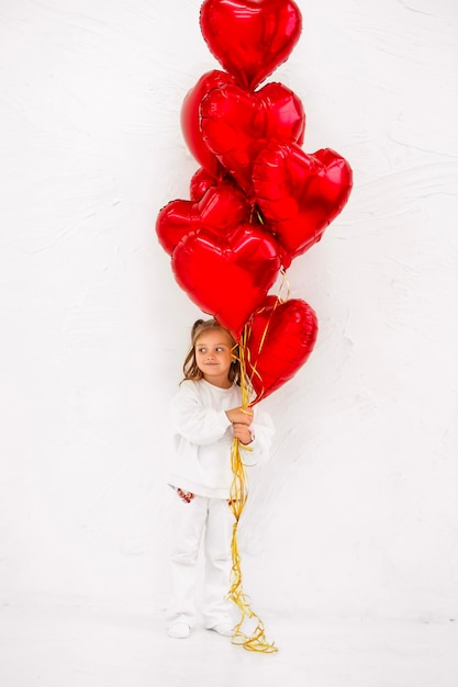 Foto una bella ragazza tiene in mano un grosso mucchio di palle di carta rossa a forma di cuore