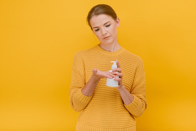 Beautiful pretty woman casually dressed uses an antiseptic sanitizer or liquid soap on her hand  cleaning concept standing 