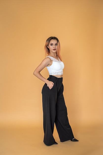 Beautiful pretty young girl posing for a portrait on a solid peach background