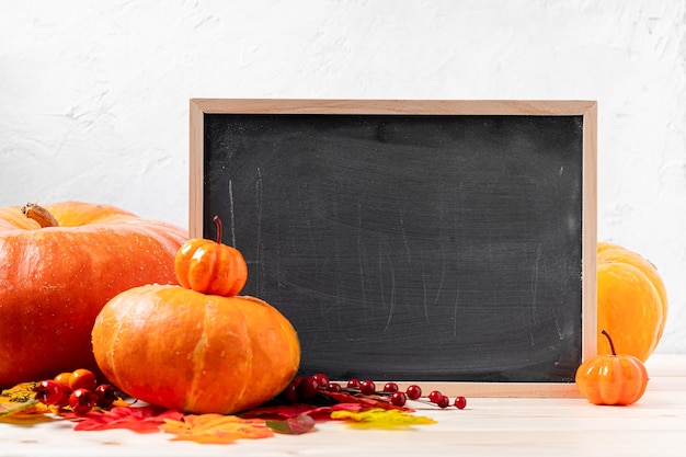 Beautiful pumpkins and fallen leaves with chalk blackboard