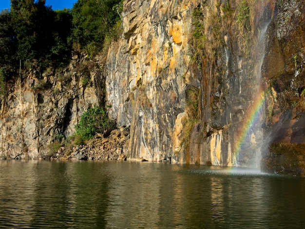 Красивая радуга над водой рядом со скалами