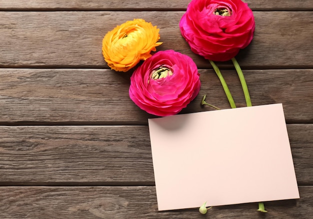 Beautiful ranunculus flowers and card on wooden background