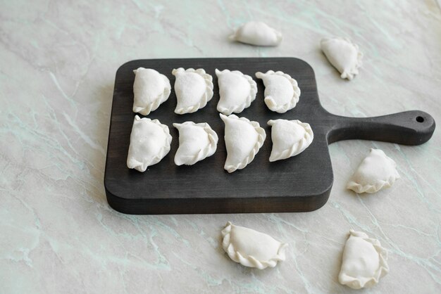 Beautiful raw stuffed dumplings on a wooden cutting board Delicious fast food