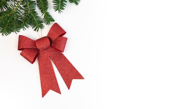 Bella decorazione di natale del regalo dell'arco rosso isolata al confine su fondo bianco. ornamenti di natale con copia spazio per il testo. elemento di design realistico per il nuovo anno per festeggiare la carta o il volantino