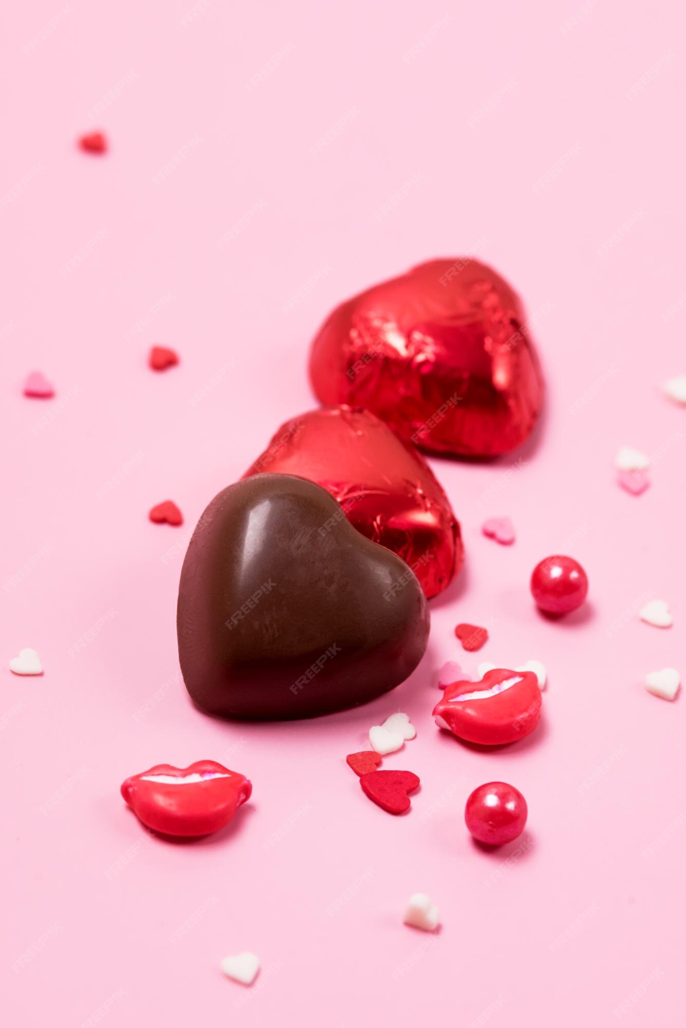 Premium Photo | Beautiful red chocolate hearts candies on pink background  valentine day holiday background vertical