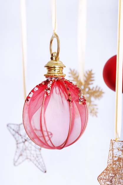 Beautiful red Christmas decorations hanging on light blurred background