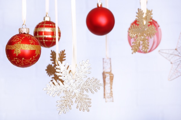 Beautiful red Christmas decorations hanging on light blurred surface