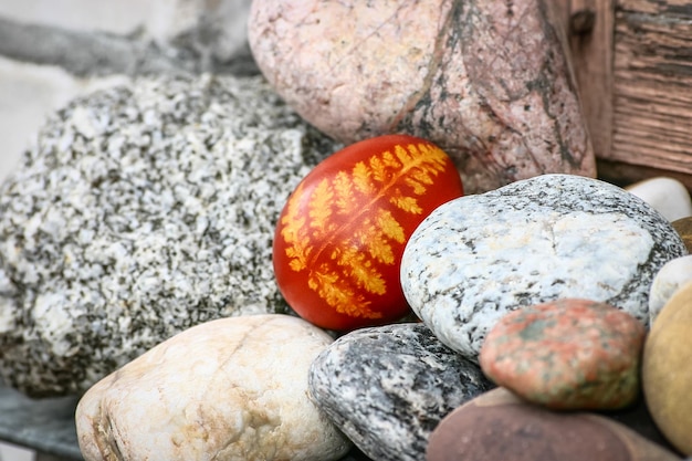 Foto un bellissimo uovo di pasqua rosso tra i ciottoli