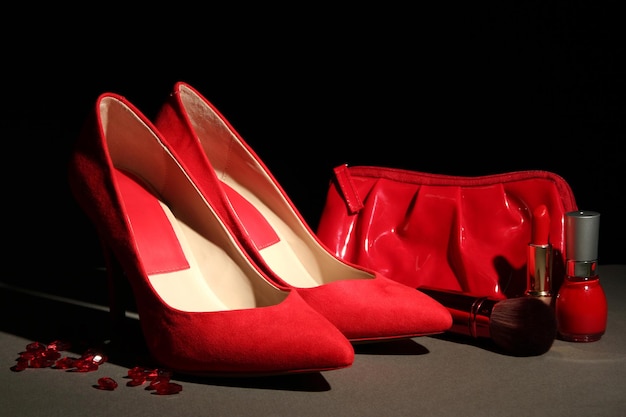 Photo beautiful red female shoes and cosmetics on black background