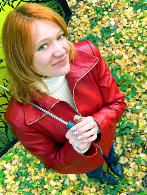 Beautiful red girl in leather jacket with umbrella