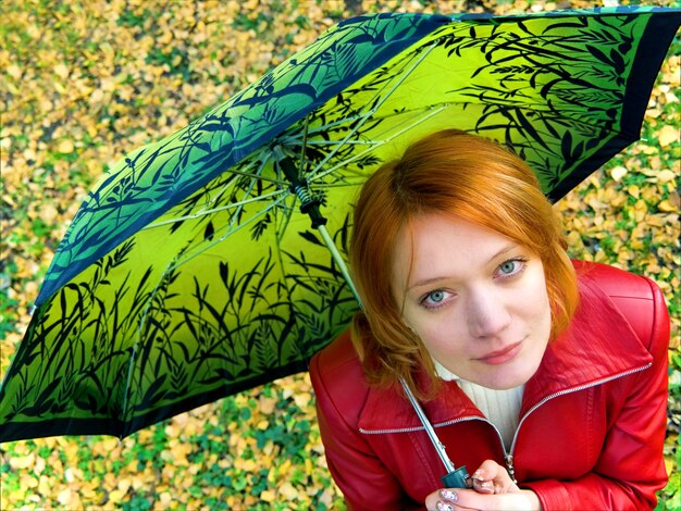 Beautiful red girl in leather jacket with umbrella