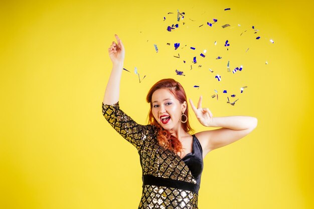 Beautiful red-haired woman dancing dance in yellow background in studio