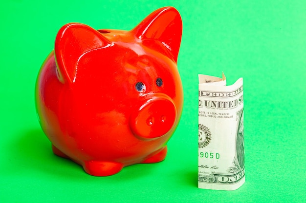 Photo beautiful red pig piggy bank with money on a green background