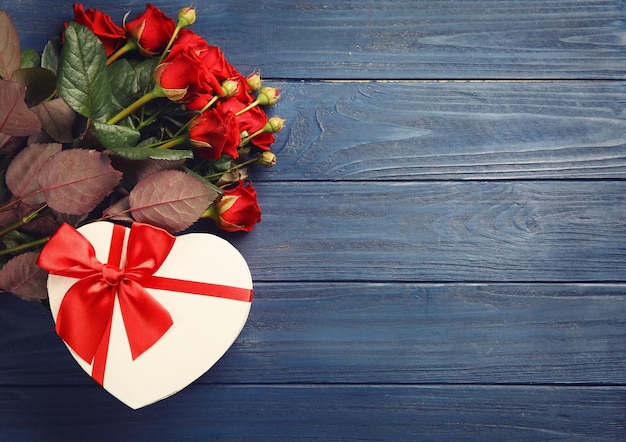 나무 배경에 아름다운 빨간 장미와 선물 상자
