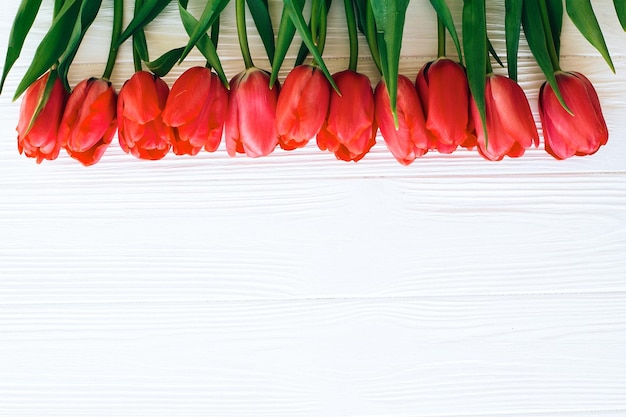 Фото Красивые красные тюльпаны на белом деревянном фоне плоской планировки с днем матери розовые тюльпаны граничат с белым деревом с пространством для текста шаблон поздравительной открытки hello spring concept