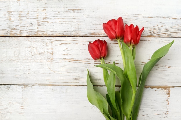 Beautiful red tulips on white wooden table