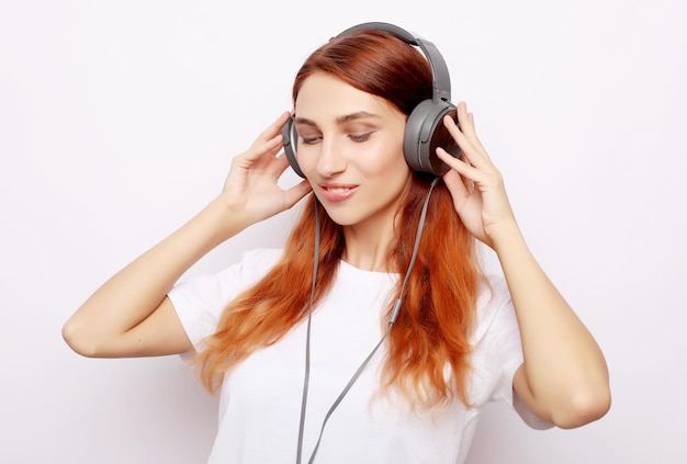 Beautiful redhair woman in headphones listening to music