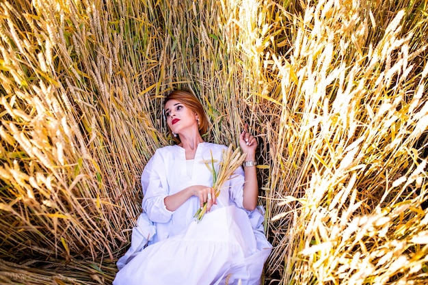 Beautiful redhead girl in a field of rye at sunset