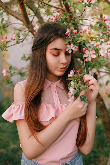 Красивая рыжая девушка весной в ветвях яблони