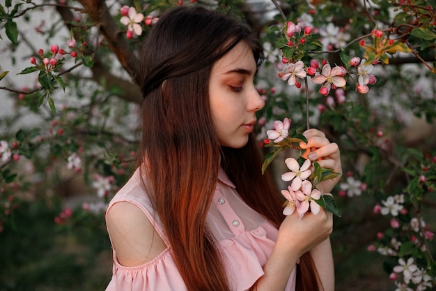 Beautiful redhead girl in the spring in the branches of the apple tree