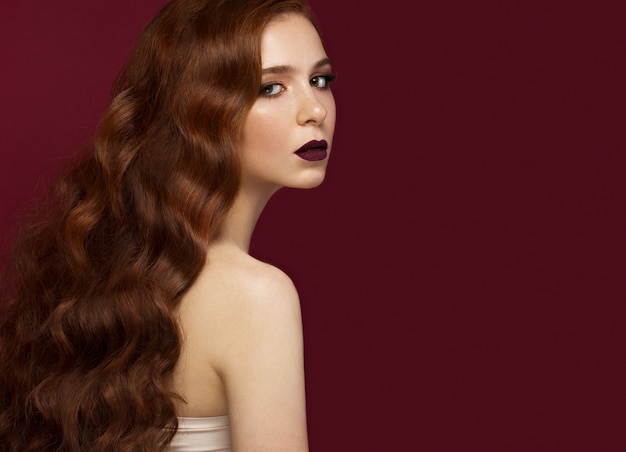 Bella ragazza rossa con i capelli perfettamente ricci e il trucco classico. volto di bellezza.