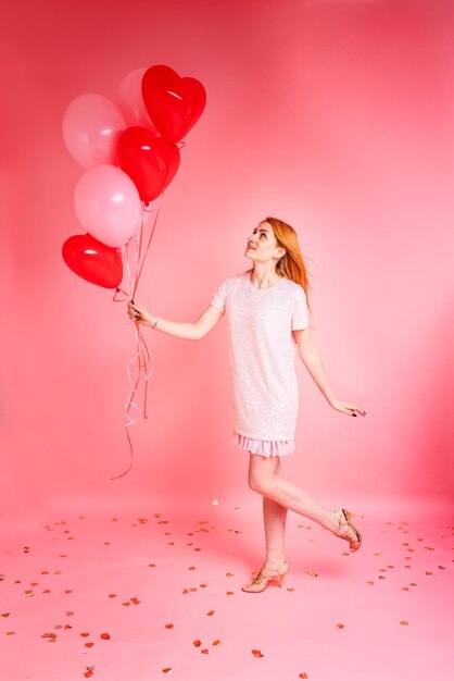 Beautiful redhead girl with red heart baloon posing. Happy Valentine's Day concept