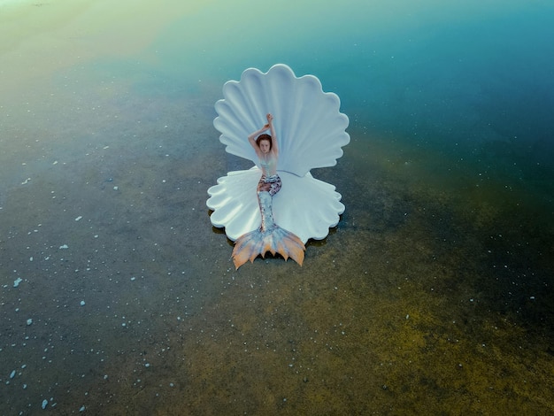 Beautiful redhead woman as mermaid with giant seashell