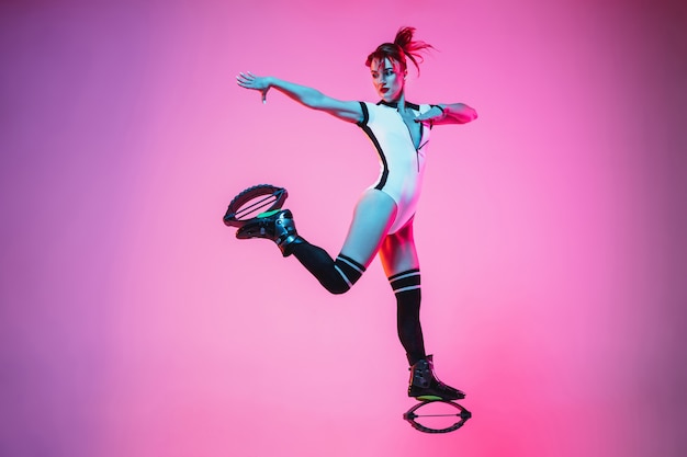 Beautiful redhead woman in a white sportswear jumping in a kangoo jumps shoes