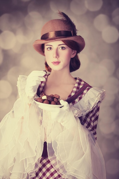 Beautiful redhead women with candy. Photo in retro style with bokeh at background.