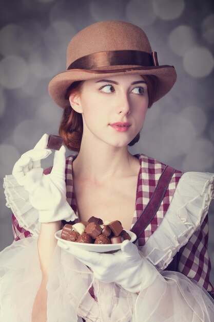 Beautiful redhead women with candy. Photo in retro style with bokeh at background.