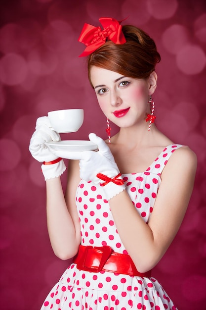 Beautiful redhead women with cup of tea. Photo in retro style with bokeh at background.