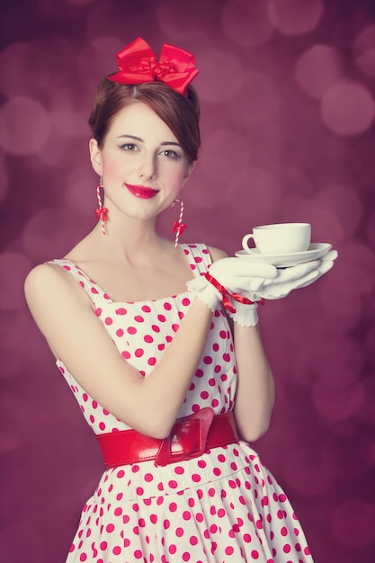 Beautiful redhead women with cup of tea. Photo in retro style with bokeh at background.