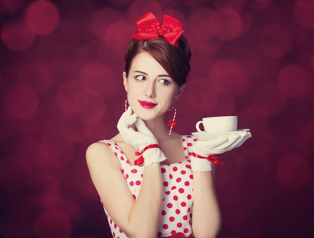 Beautiful redhead women with cup of tea. Photo in retro style with bokeh at background.