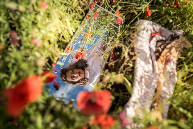 Photo beautiful reflection of a girl in the mirror on a poppy field. summer time