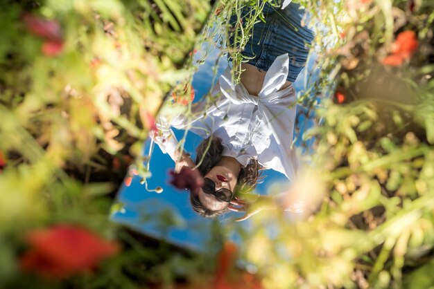 Foto bellissimo riflesso di una ragazza allo specchio su un campo di papaveri. estate