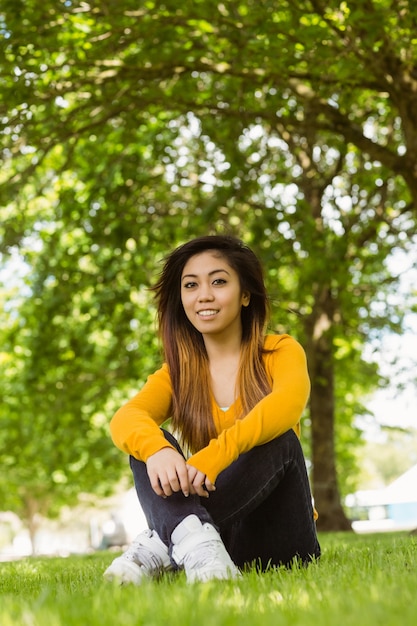 Beautiful relaxed woman sitting on grass at park