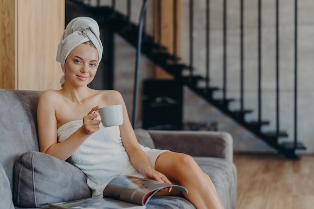 Красивая расслабленная женщина, завернутая в полотенце, пьет чай