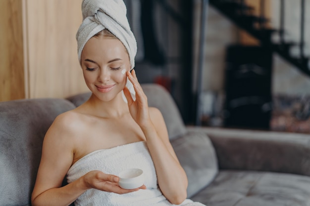 Beautiful relaxed woman wrapped in towel drinking tea