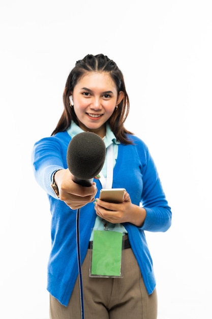 A beautiful reporter in blue shirt and blue cardigan standing with phone at her hand and hand over a