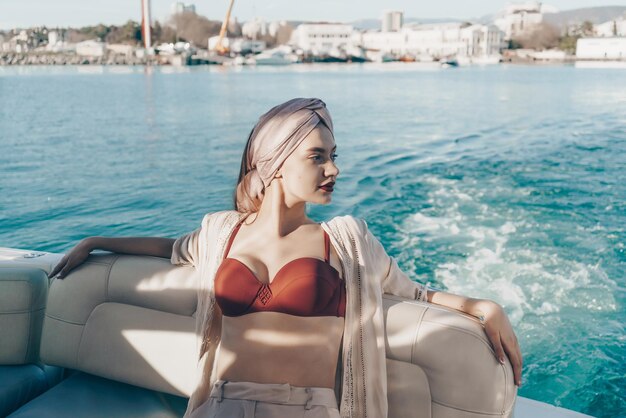 Beautiful rich woman in a red swimsuit enjoys relaxing on a\
yacht sailing to the islands